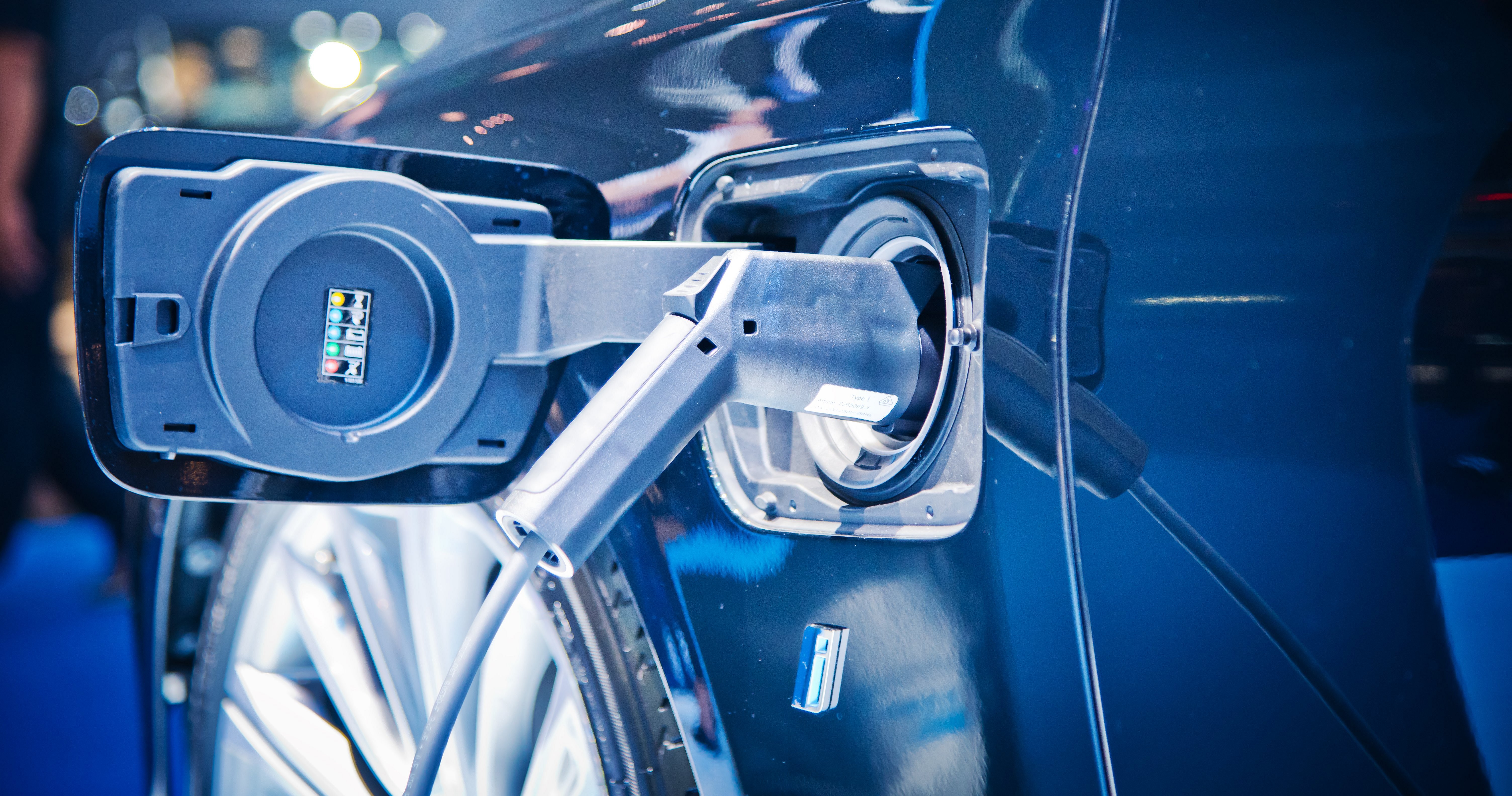 Nahaufnahme der Ladebuchse und des angeschlossenen Ladekabels an einem dunkelblauen E-Auto